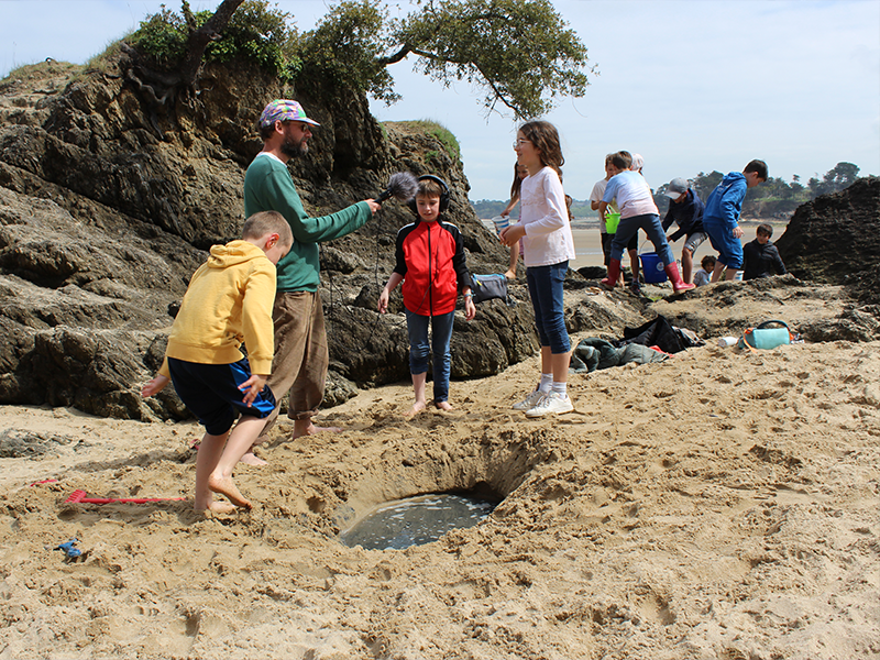 Les enfants et Marc sont à la mer pour observer et écouter la nature.
